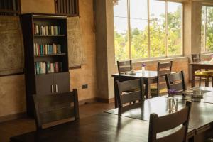 a dining room with tables and chairs and a book shelf at Jasmin Villa Ayurveda Resort in Negombo