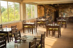 a dining room with tables and chairs and windows at Jasmin Villa Ayurveda Resort in Negombo