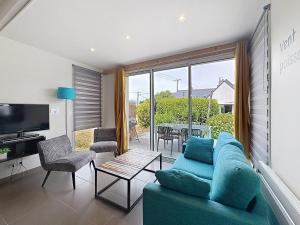 a living room with a blue couch and a table at Les Gîtes du Pêcheur in Erquy