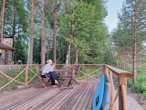 a woman sitting at a table on a wooden deck at Kelola Cottage in Keyritty