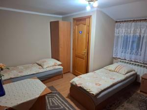 a small room with two beds and a door at Agroturystyka nad rzeczką in Szymany