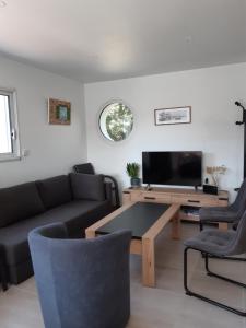 a living room with a couch and a television at Maison Tamaris avec jardin et clos in Quiberon