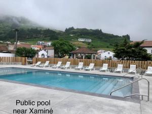 a pool with white lounge chairs next to a fence at Xaminé in Água Retorta