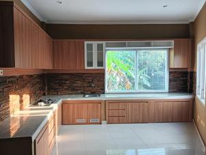 a kitchen with wooden cabinets and a large window at Alam Sari GUEST HOUSE in Tabanan