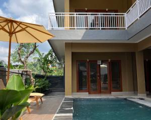 a house with a swimming pool and an umbrella at Alam Sari GUEST HOUSE in Tabanan
