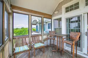 a porch with chairs and a table and windows at 2433 - Bella Bay in Duck