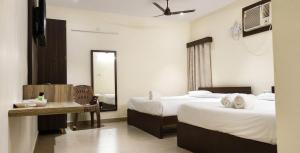 a hotel room with two beds and a mirror at Jazz Inn in Tiruvallūr