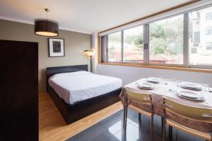 Studios Porto Solar في بورتو: غرفة نوم بسرير وطاولة مع كراسي