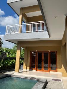 a house with a swimming pool and a balcony at Alam Sari GUEST HOUSE in Tabanan