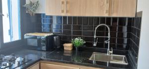 a kitchen with a sink and a black tiled wall at Precioso estudio a pie de playa in Cabo Negro