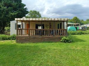 a small cabin with a porch in the grass at Mobil home Vegas in Blangy-le-Château
