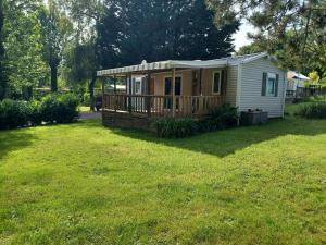 a tiny house with a deck on a yard at Mobil home Vegas in Blangy-le-Château