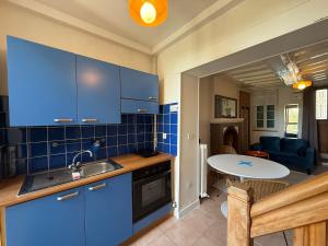 a kitchen with blue cabinets and a table in a room at Le Cosy in Coutances