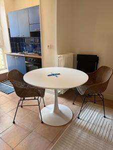 a white table in a kitchen with two chairs at Le Cosy in Coutances +5 photos