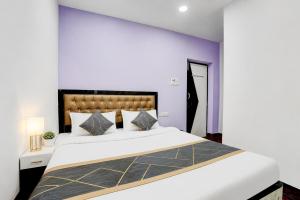 a bedroom with a large white bed and purple walls at Triotel Inn in Dhanbād