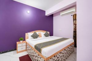 a bedroom with a bed with a purple wall at Triotel Inn in Dhanbād