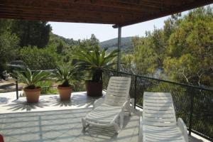 two white chairs and palm trees on a balcony at Apartment Nono Ivo in Vis