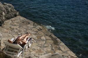 a man sitting in a chair next to the water at Apartment Nono Ivo in Vis