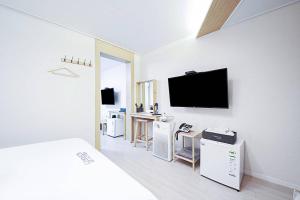 a white room with a bed and a flat screen tv at 통영호텔조선 in T'ongyŏng