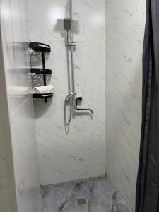a shower in a bathroom with white marble walls at Royal Hotel Navoi in Navoi +40 photos