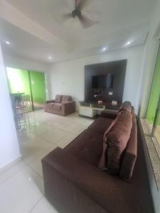 a living room with a brown couch and a tv at Sobrado Mobiliado in Três Lagoas
