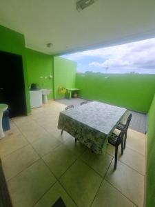 a room with a table and chairs and a green wall at Sobrado Mobiliado in Três Lagoas