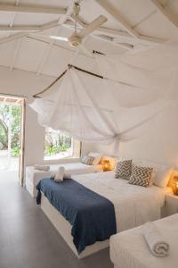 two beds in a white room with a ceiling at Casa Rosario in Isla Grande