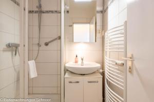 a bathroom with a white sink and a shower at Waterkant in Schilksee +5 photos