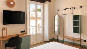 a bedroom with a shower and a television on a wall at Hotel Casa Beatas in Málaga