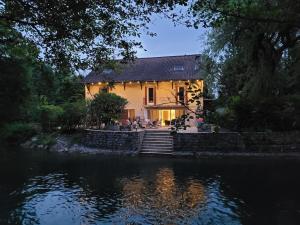 a house sitting on the side of a river at La maison du lac in Vions