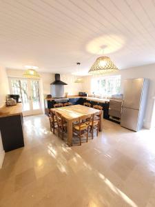 a large kitchen with a table and a refrigerator at La maison du lac in Vions