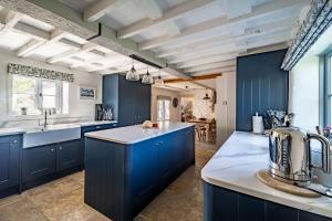 a kitchen with navy blue cabinets and a white counter top at Ruthie Cottage in Bacton