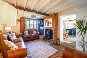a living room with leather furniture and a brick wall at Ruthie Cottage in Bacton