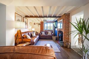 a living room with leather furniture and a brick wall at Ruthie Cottage in Bacton