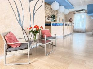 a lobby with two chairs and a table with a vase of flowers at Lucky Fish Jurmala in Jūrmala