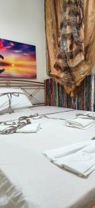 a bed with white sheets and a tv on the wall at Mama's Home in Chios