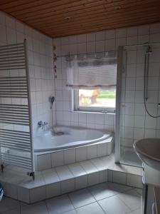 a bathroom with a tub and a sink and a window at Ferienwohnung Heck in Waldeck +15 photos