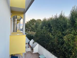 a yellow and white building with a balcony with trees at Residence Perla - Salve in Salve
