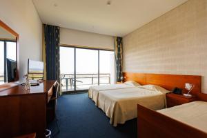 a hotel room with two beds and a desk at Hotel Colombo in Vila do Porto +21 photos