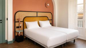 a bedroom with a white bed and a orange wall at Hotel Casa Beatas in Málaga