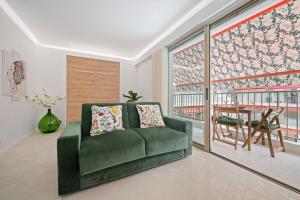a living room with a green couch and a table at LAMAZONICO - Proche Centre - Terrasse Clim Plage in Menton