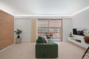 a living room with a green couch and a tv at LAMAZONICO - Proche Centre - Terrasse Clim Plage in Menton