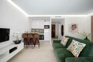 a living room with a green couch and a kitchen at LAMAZONICO - Proche Centre - Terrasse Clim Plage in Menton