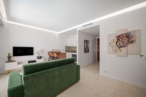 a living room with a green couch and a television at LAMAZONICO - Proche Centre - Terrasse Clim Plage in Menton