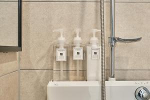 a shower with four bottles of soap in a shower stall at Seoul Jongno Hostel in Seoul