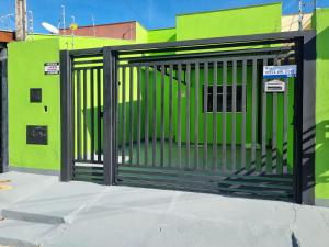 a gate on the side of a green building at Casa Atenas 2 in Três Lagoas