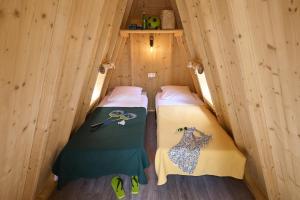 two beds in a wooden cabin with scissors on them at Camping les Chalands Fleuris in Saint-André-des-Eaux