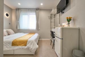 a small bedroom with a bed and a refrigerator at Seoul Jongno Hostel in Seoul