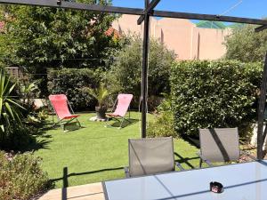 two pink chairs and a table in a garden at Chez vero in Le Boulou