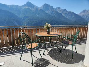 Ein Tisch und Stühle auf einem Balkon mit Bergblick in der Unterkunft Chasa Foppa in Scuol